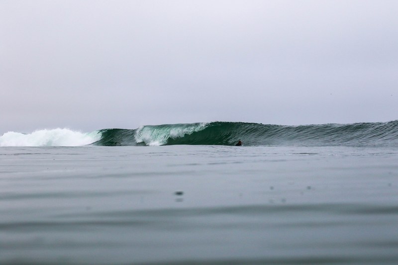 surfer in the water going towards big surf wave at newport beach, wavy sea and overcast sky 4k