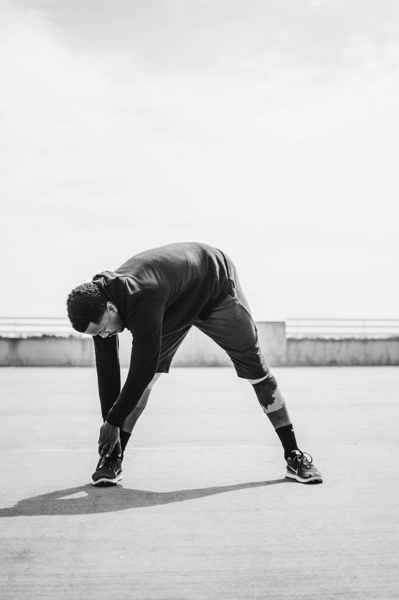 a person reaching down to their right foot while performing a stretching exercise, _person stretching their legs 4k