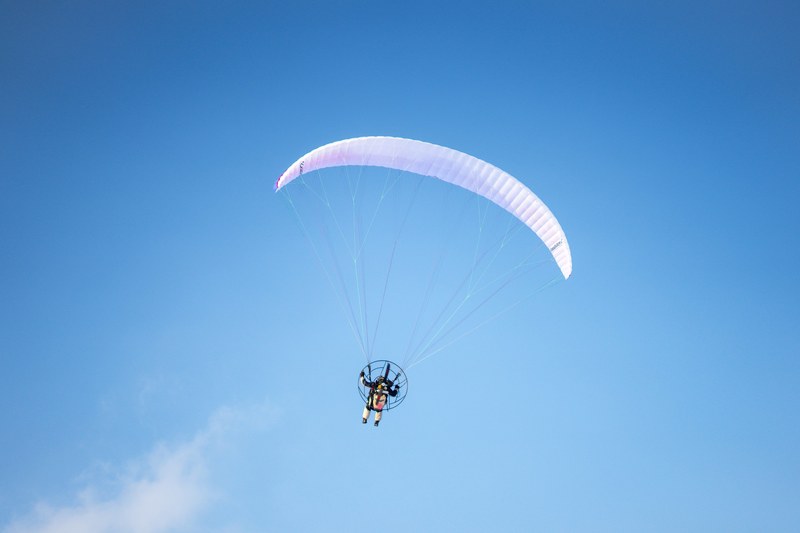 parachute glider flies solo across a clear blue sky, solo parachuting 4k