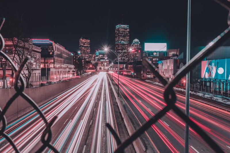 an image displaying headlight light trails from behind a fence at fenway park, bright lights 4k