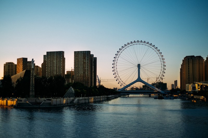 a waterfront with a ferris wheel over the water in the evening, ferris wheel over water 4k