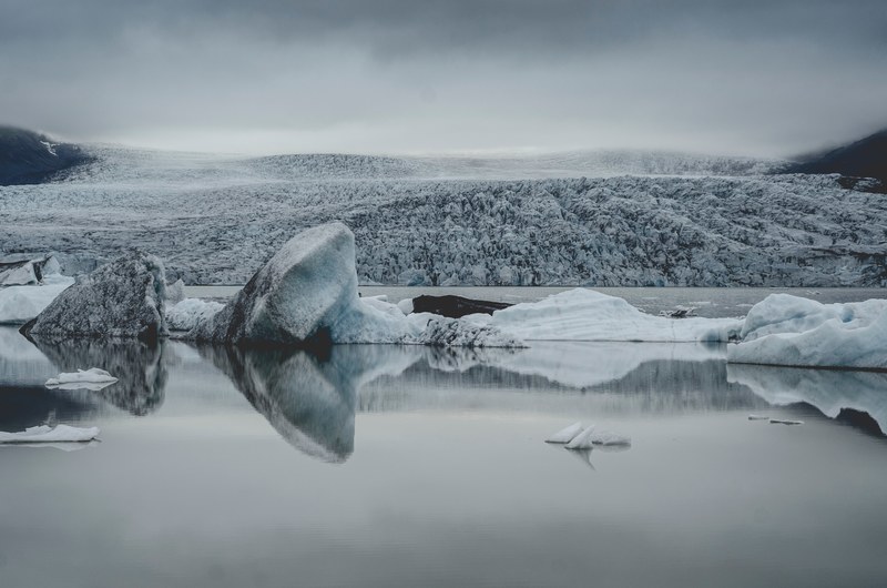 a still lake with glaciers jutting out with a snowy wilderness receding into the horizon, winter wilderness lake 4k