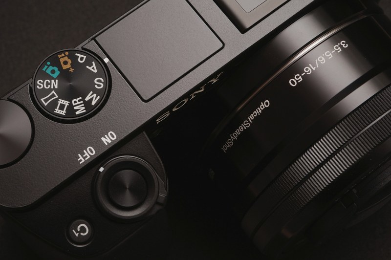 macro of top of black sony camera with dial and on off switch, macro sony camera 4k