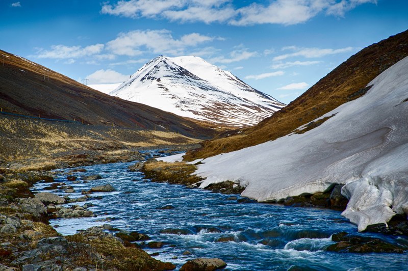 a river in a valley on iceland is flowing in the direction of a snowy mountain, river between mountains 4k