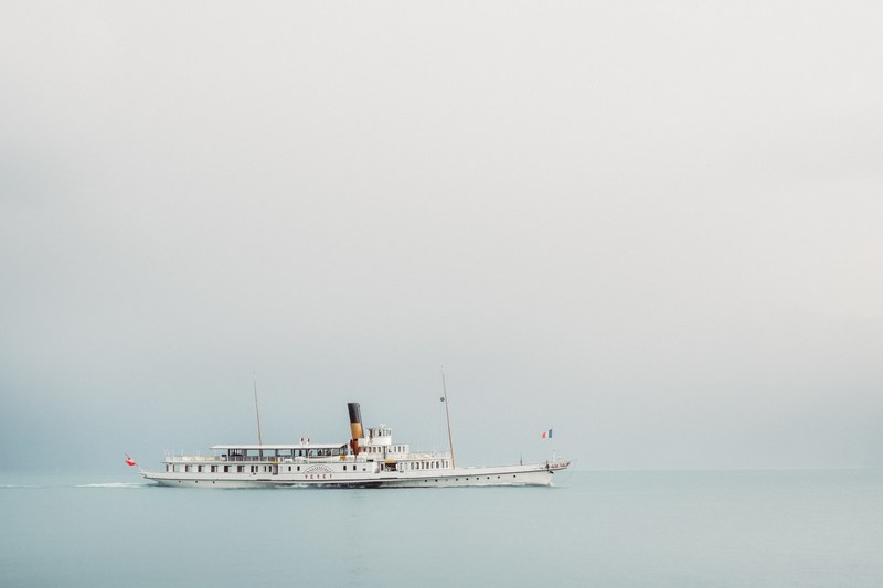 a beautiful steamboat gliding over the calm ocean in vevey on a foggy day, ocean vessels in vevey 4k