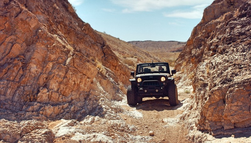 jeep truck drives through rough terrains in a desert canyon in nevada, black jeep nevada desert 4k