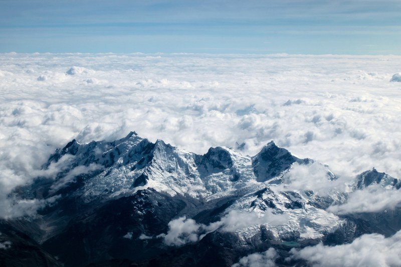 a snowy mountain ridge with thick clouds stretching over the land to the horizon, sea of clouds behind mountains 4k