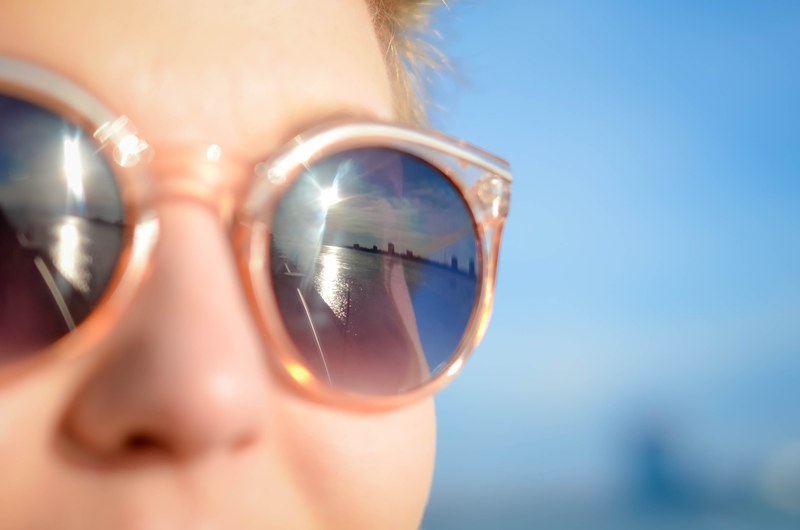 sun reflects off the sunglass of pretty woman relaxing in detroit beach, woman wearing sunglass detroit 4k