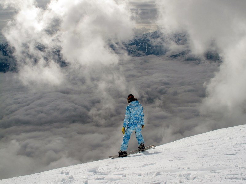 a snowboarder overlooking a cloudy and snow covered hill, snowboarder on a cloudy hill 4k