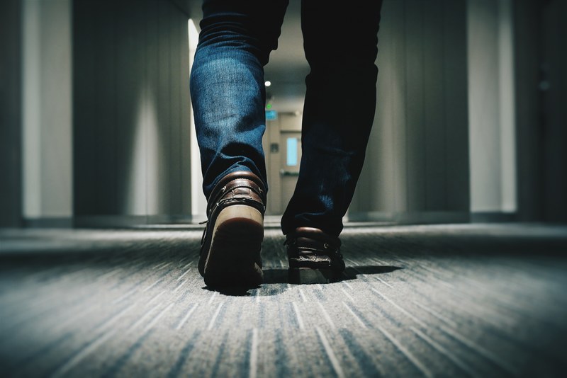a low shot of a person in jeans walking through a hotel corridor, feet in a hotel corridor 4k