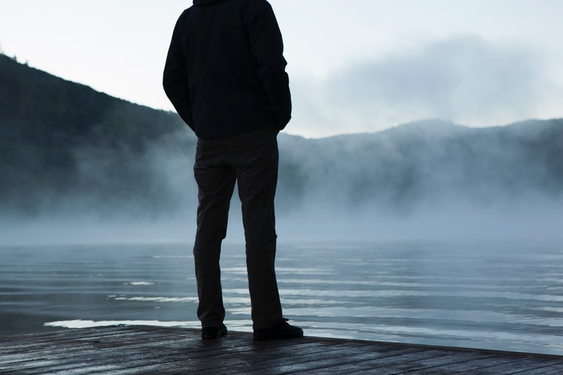 silhouette of person standing on the seashore of a misty lake, contemplating by the lake 4k