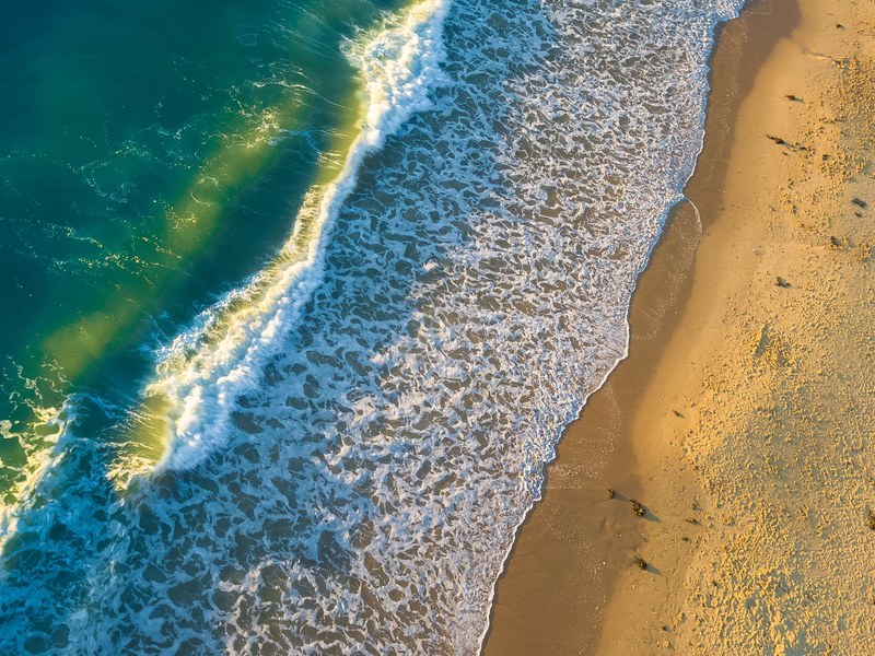 drone view of ocean waves crashing on the sand beach at roker beach, summer sunrise waves 4k