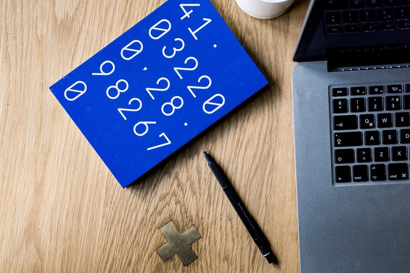 a blue notebook with numbers on its cover on a desk next to a laptop and a pen, blue number notebook 4k