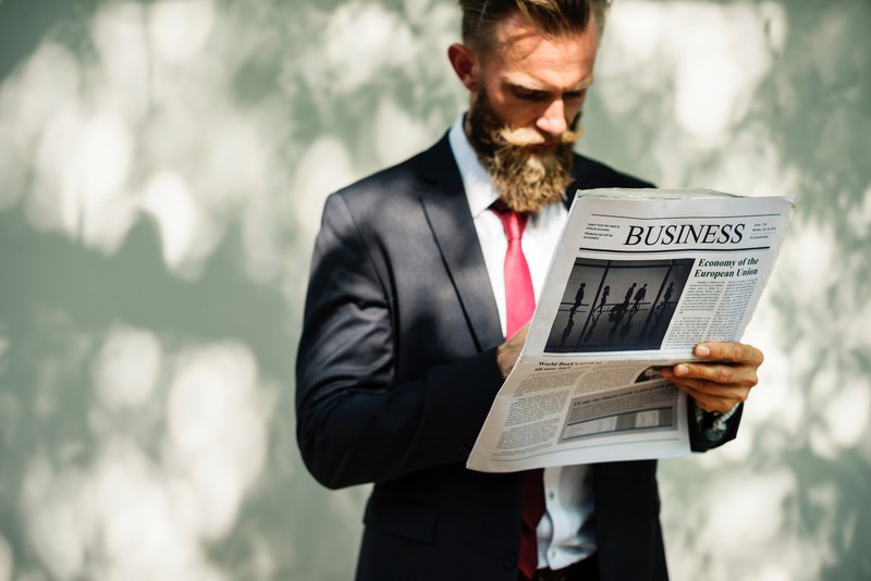 a bearded man in a suit reading the business section of a newspaper, _reading business newspaper 4k