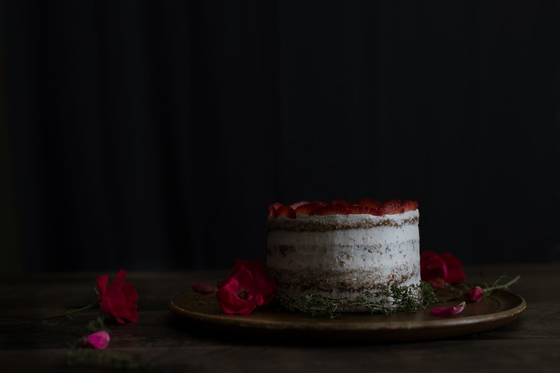 a cake on a platter with red rose petals on top of it, _strawberry thyme cake 4k