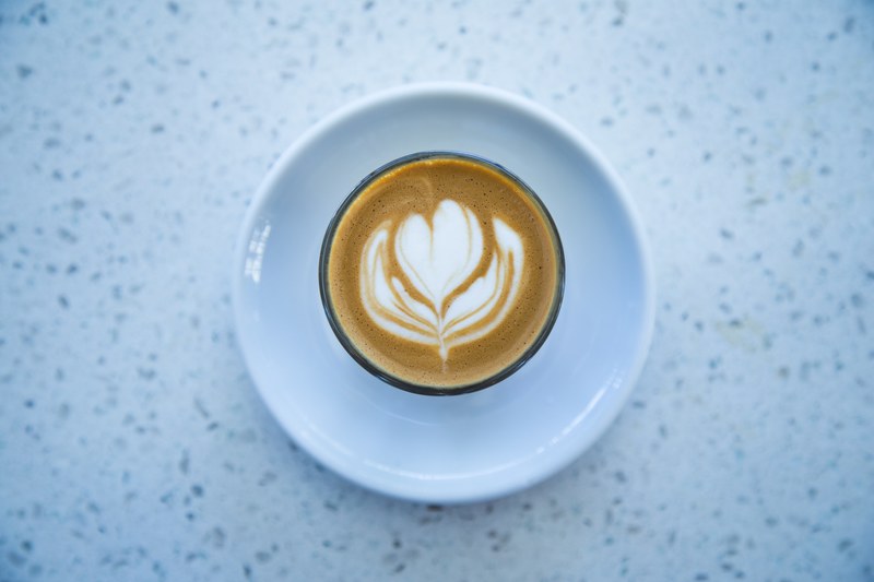 latte coffee foam artwork in white cup and saucer on white marble texture table pasadena, latte art in pasadena 4k
