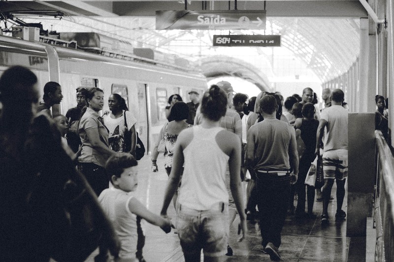 a black and white shot of people walking across a railway station, train station crowd in black and white 4k