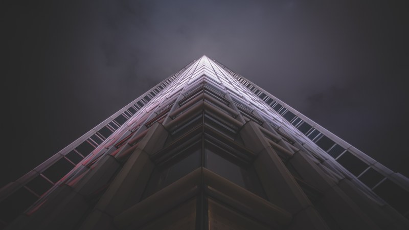 very tall skyscraper building with shadow at base and pink and white light at top, tall skyscraper in pink light 4k
