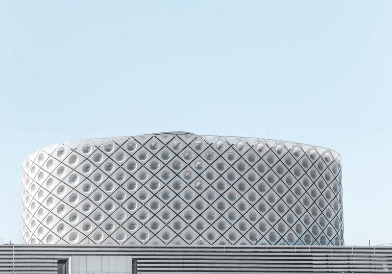 a circular arena with a dotted pattern on its white facade in madrid, white dotted arena facade 4k