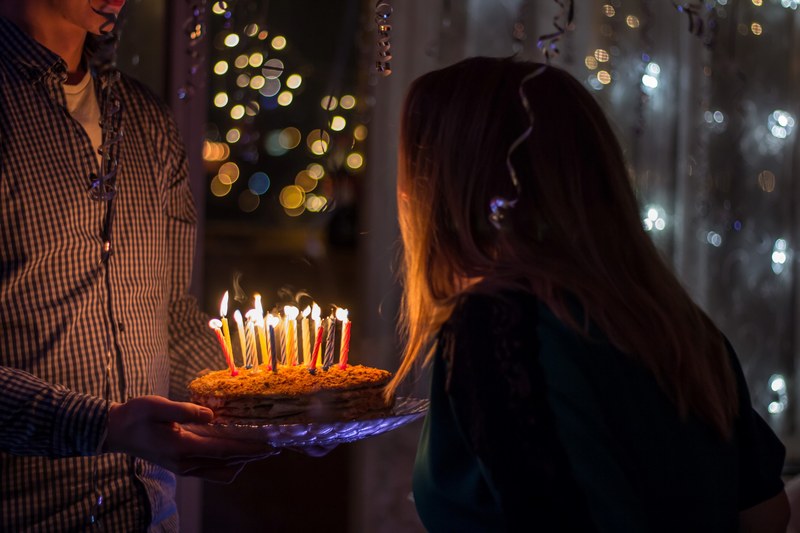 a man bringing a birthday cake with candles to a woman in a room filled with balloons, happy birthday 4k