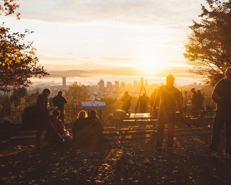 a group of people watching the sunrise or sunset from a hilltop lookout spot at pittock mansion, people at a view point of a cityscape 4k