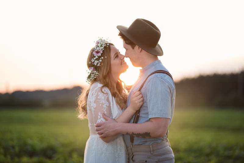 bride with flower crown and groom with hat smile at each other at sunset, wedding smile at sunset 4k