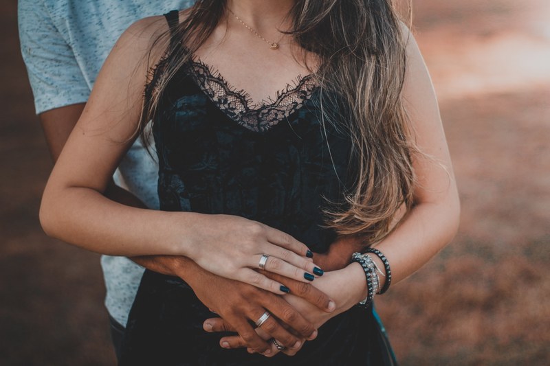 torso of teenage girl held gently from behind by her boyfriend hands clasped, clasped hands around waist 4k