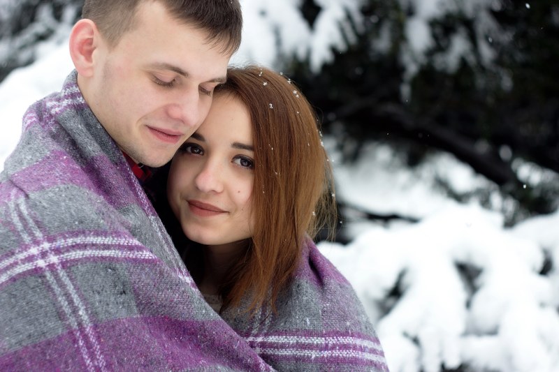 a happy man and woman wrapped in a blanket together next to a snow covered tree, _man and woman in blanket 4k