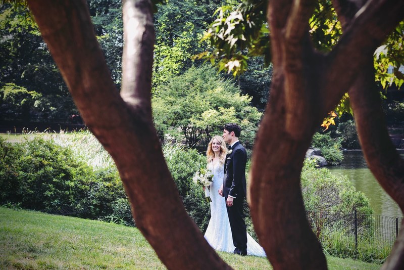 wedding couple stands in central park south holding hands in front of a pond, newlyweds at central park south 4k