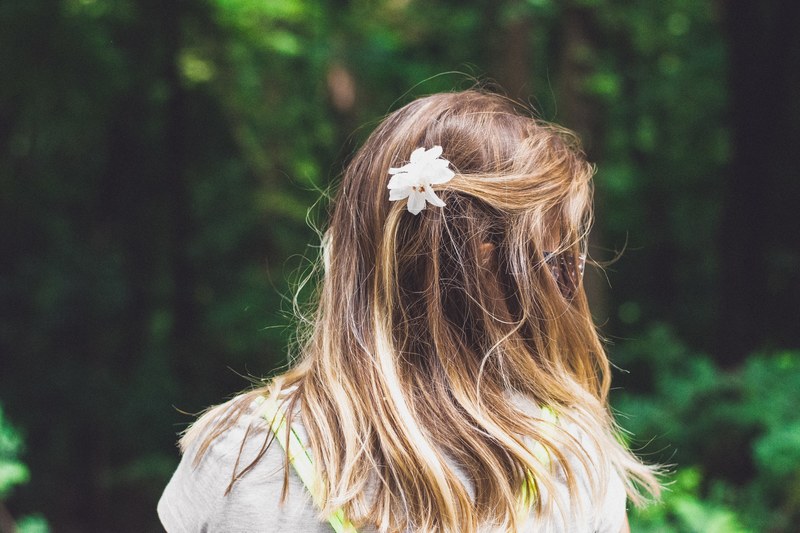 the back of the head of a dark blonde woman with a white flower in her hair, white flower in blonde hair 4k