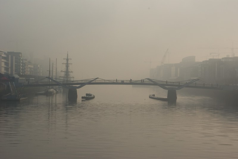 industrial city structures by a bridge over foggy water, foggy city silhouettes 4k