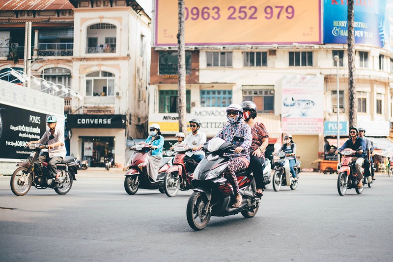 diverse group of people riding vespas and motorcycles down a city street, group of bikers 4k