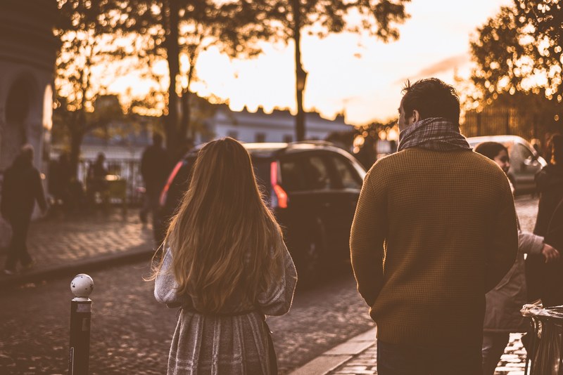 a woman and a man walk through a crowd by a cobblestone street, people crossing stone street 4k