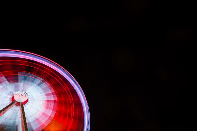 a partial image of a big red illuminated ferris wheel spinning at a fair, colorful red wheel spinning at a fair 4k