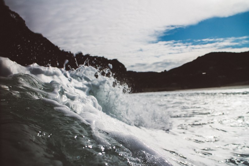 a close up of a frothy foamy wave breaking in piha, foaming sea wave 4k