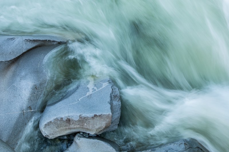 swirling sea waves foaming against smooth rocks, rocks under swirling waves 4k