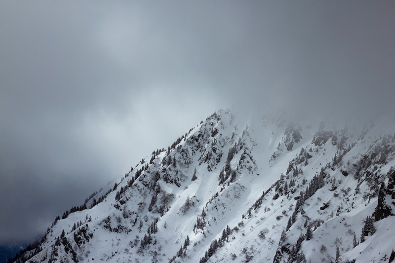 a snow covered mountains summit shrouded in thick fog, mountain summit in mist 4k