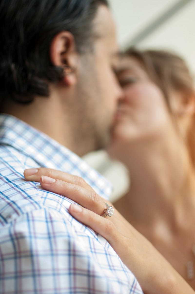 a couple kisses_ her hand is on his shoulder showing off her engagement ring, kissing with engagement ring 4k