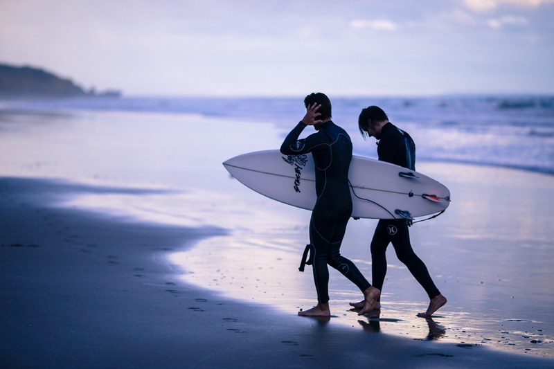 two surfers walking on the wet sand beach after the sunset in torquay, torquay beach surfers 4k