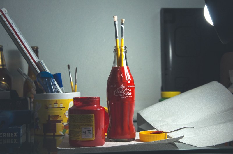 a coca cola bottle used as a beaker to hold paint brushes with other beakers, beakers of paint brushes 4k