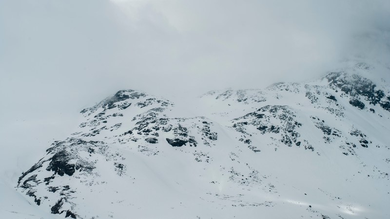 a mountain ridge covered in a heavy layer of snow under a white sky, white wilderness 4k
