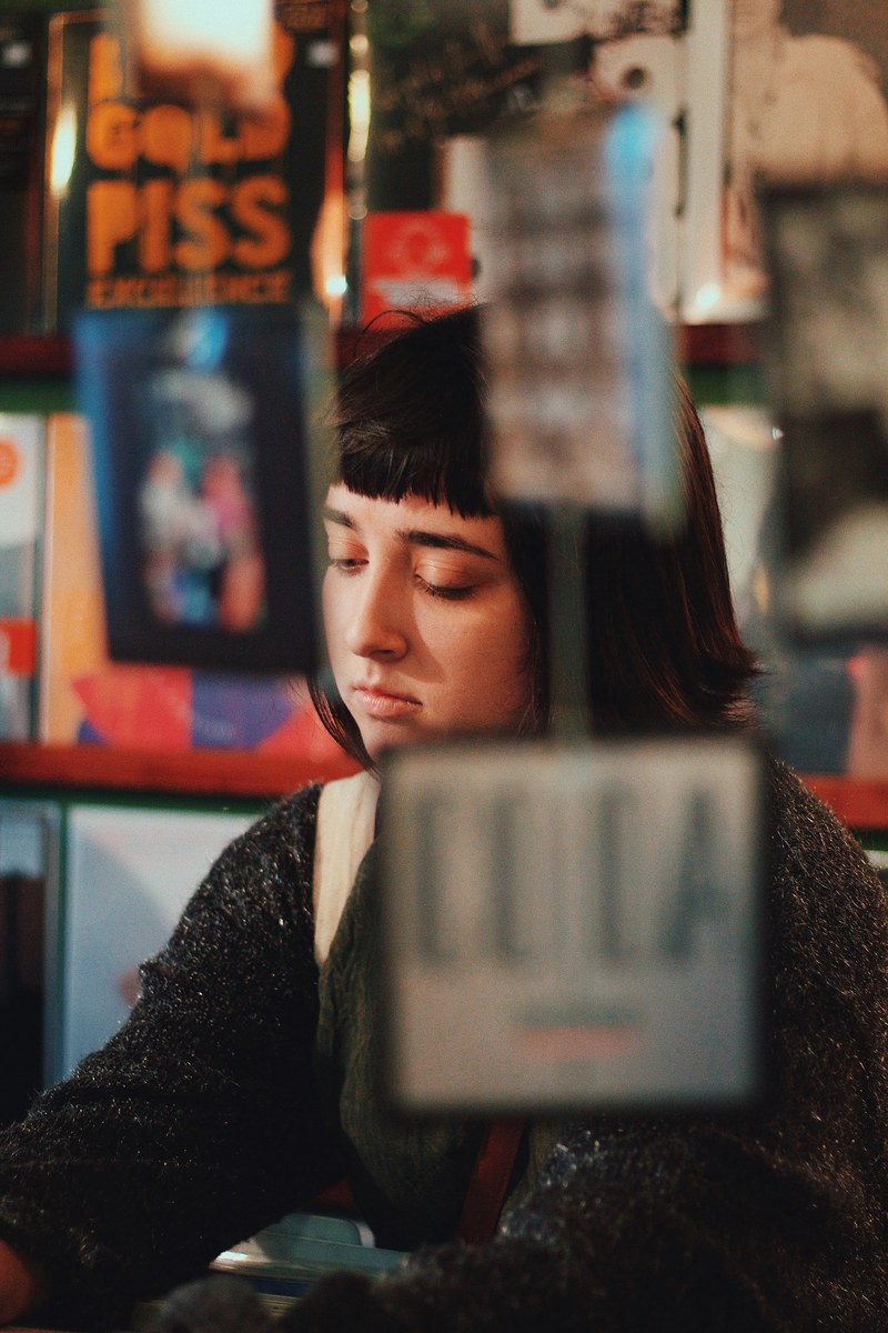 a young woman sitting behind a counter in a store, young woman behind a counter 4k