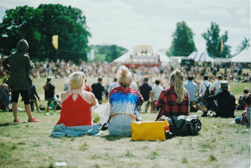 young women sitting at the back of an audience at a music festival, young women at a music festival 4k