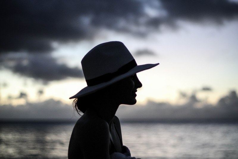 the silhouette of a woman wearing a hat during sunset at waimea bay, watching the sunset 4k