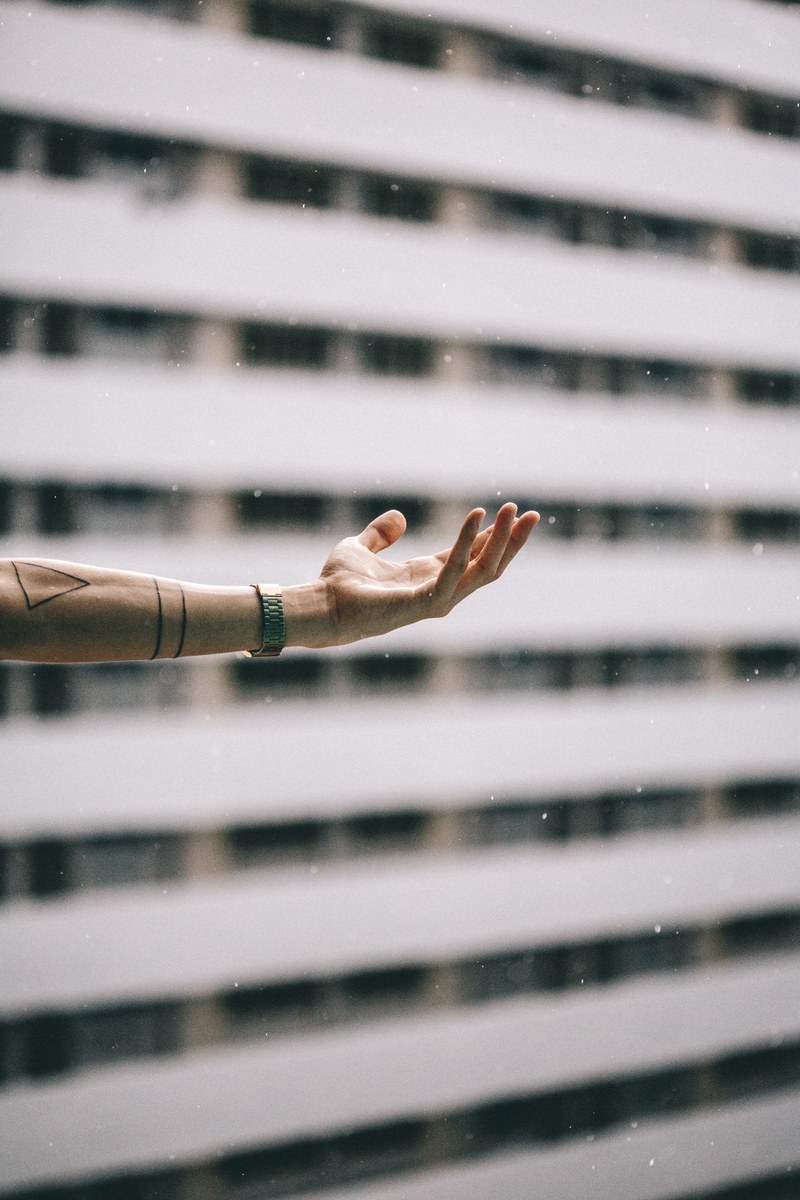 outstretched tattooed arm in front of building, outstretched arm 4k