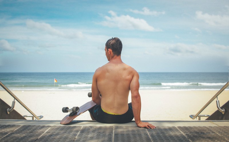 muscular man sitting down to enjoy some quiet with his skateboard at surfers paradise, skateboarding at surfers paradise 4k