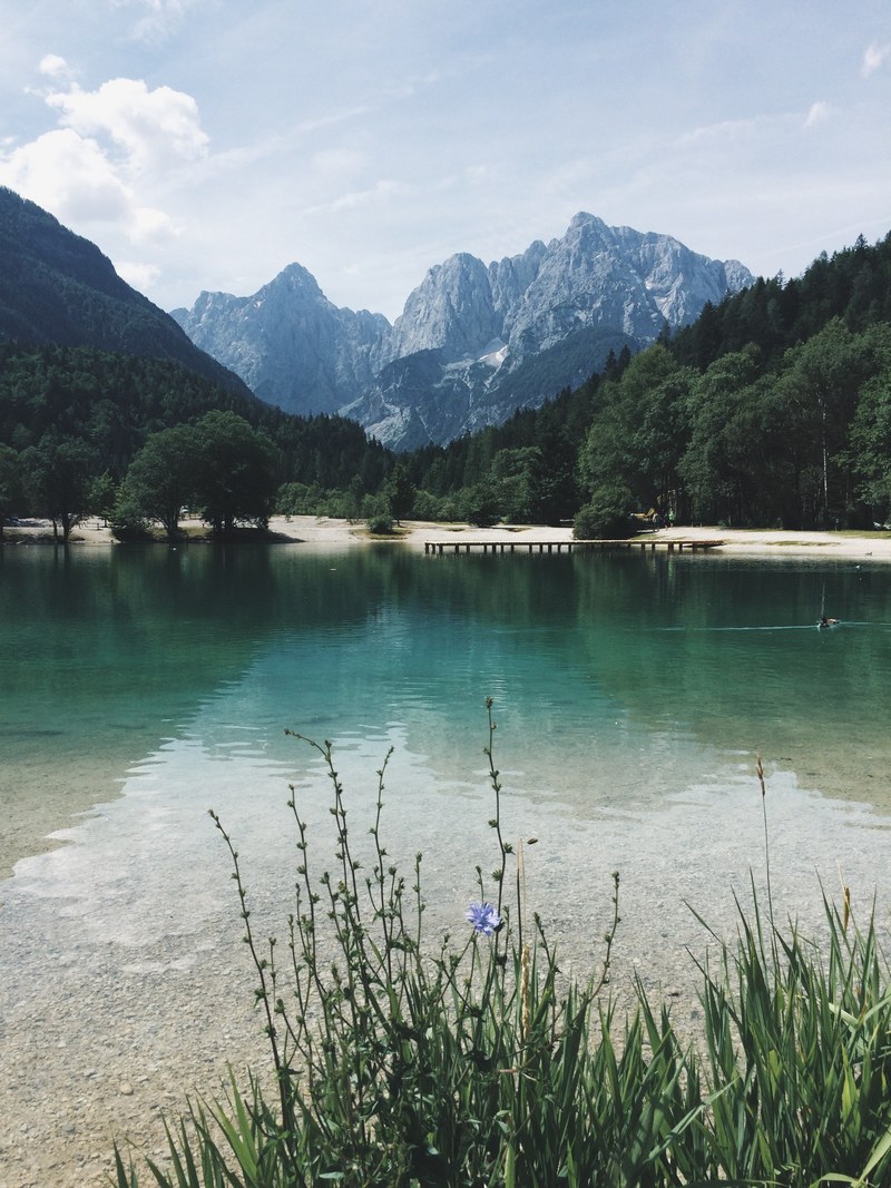 a jade green lake with a pier on the other shore near granite mountains, green lake with a pier 4k