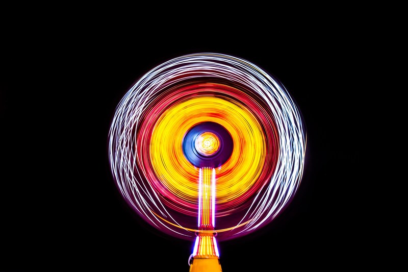 a bright white yellow and red light painting made by a ride at a fair in cocoa beach, illuminated cocoa beach carnival ride 4k