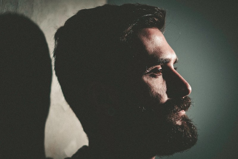 a close up bearded man with a serious expression casts a shadow, bearded man casts a shadow 4k