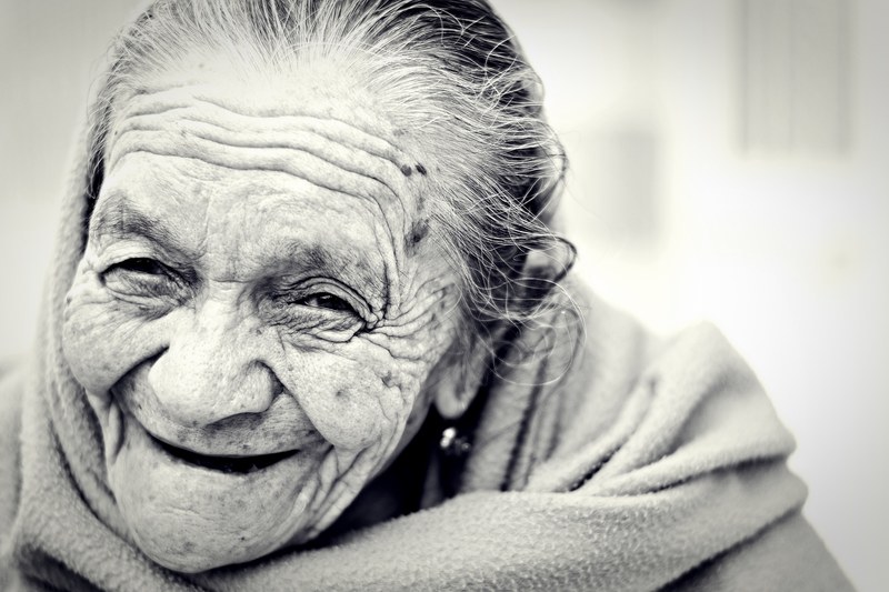 elderly woman with care worn face laughs in black and white photo, grandmother laughs 4k